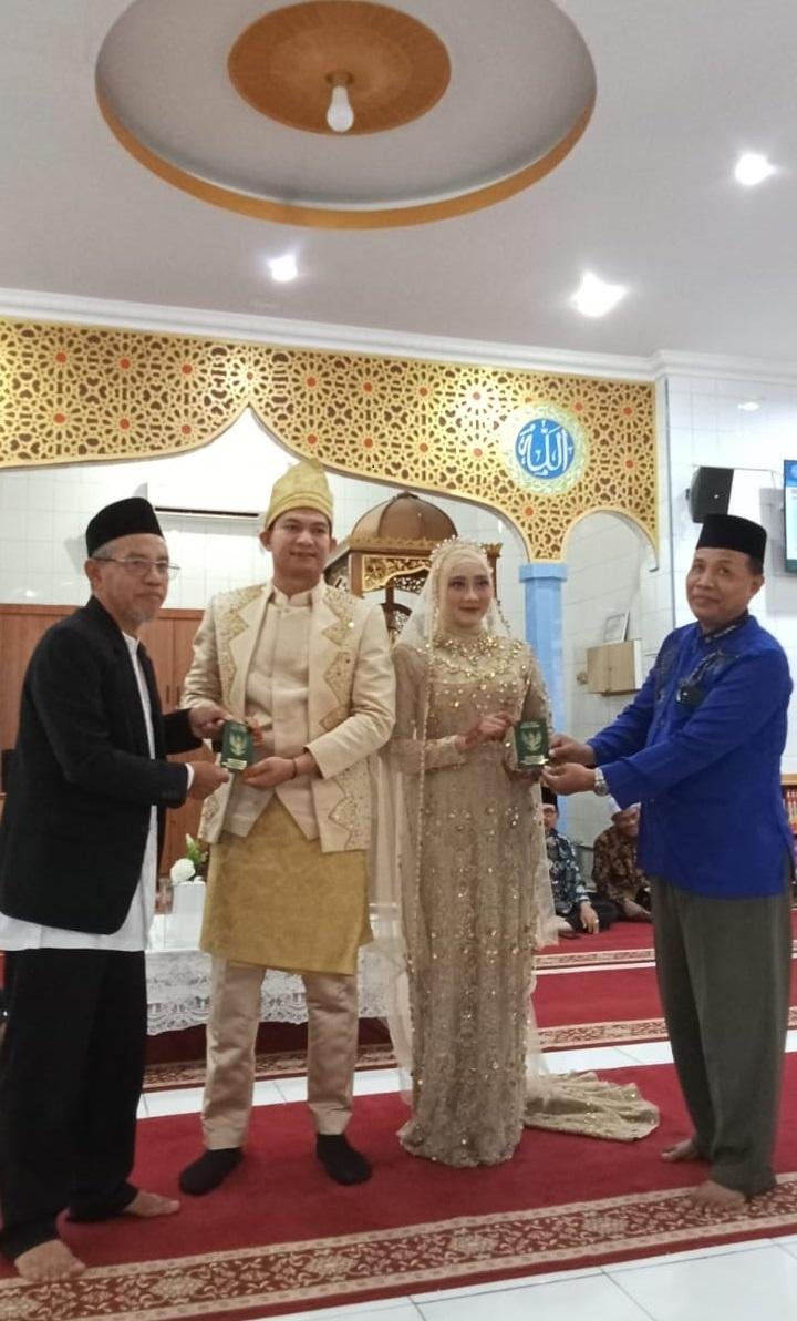 Penghulu Muda KUA Payung Sekaki Serahkan Buku Nikah Kepada Pengantin